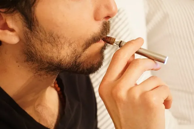A bearded man vaping